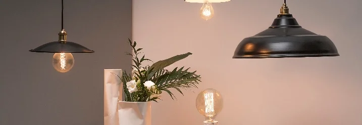 Vier schwarze Hängelampen über einem Tisch
